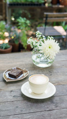 Hot coffee and brownie cake on a wooden table.