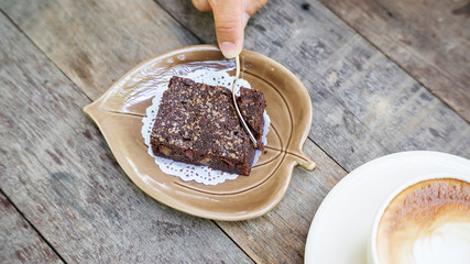 Hot coffee and brownie cake on a wooden table.