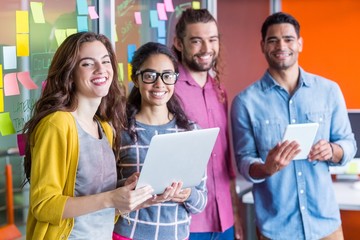 Smiling executives using digital tablet and laptop