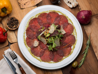 Serving of carpaccio on a white plate in a restaurant