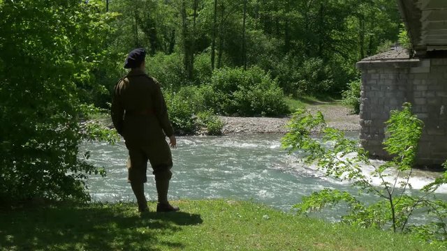 man with old french military uniform, smoking cigarette near the river