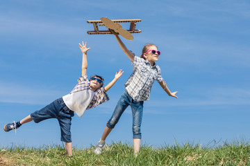 Little kids playing with cardboard toy airplane in the park at the day time.