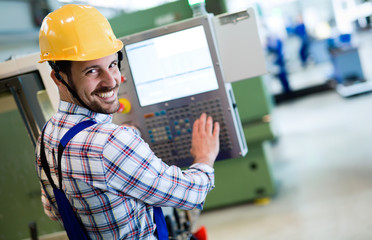 Industry Worker entering data in CNC machine at factory