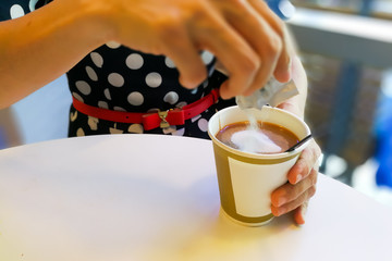 Fototapeta na wymiar Hand pouring unhealthy non dairy creamer from sachet into coffee