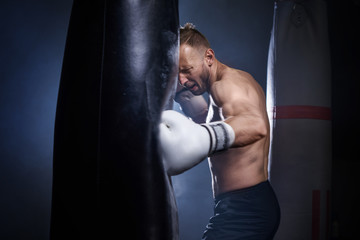 Male boxer using punch bag during training .