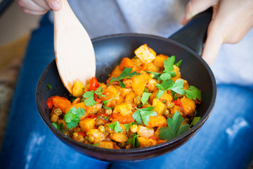 Woman holds a frying pan with vegetable ragout. Healthy food.