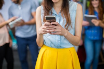 Mid section of female executive using mobile phone