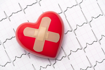 Red heart with adhesive plaster on electrocardiogram (ECG, EKG)