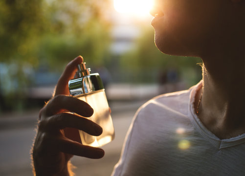 young man with male perfume over nature background