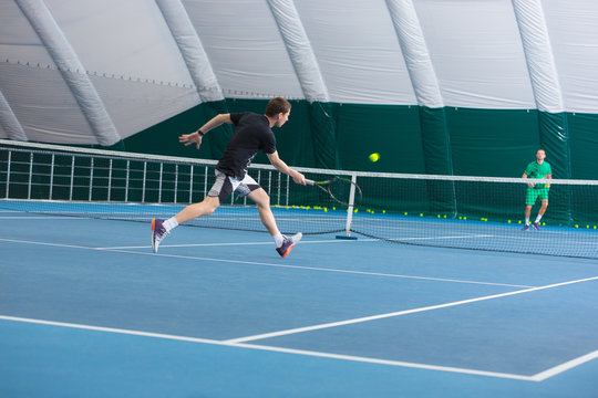 The young man in a closed tennis court with ball