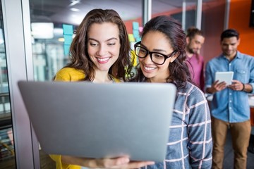 Two smiling female executives using laptop