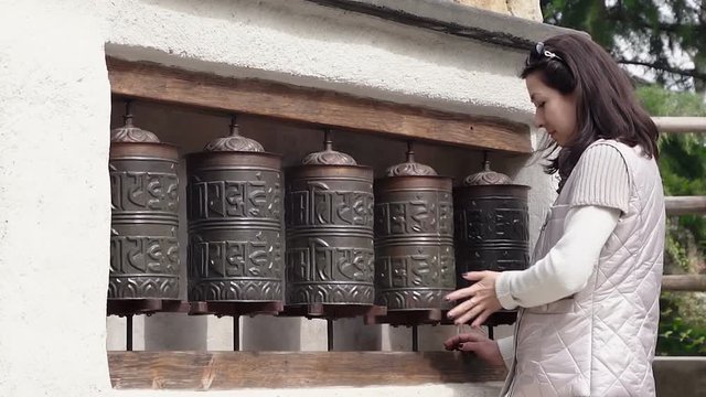 European woman spins prayer wheels, HD 1080p