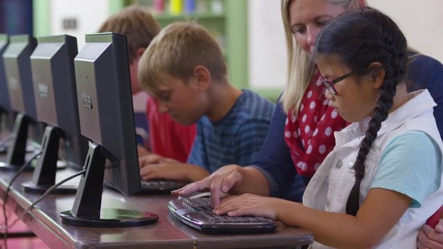Teacher and student work on computer in school classroom