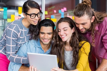 Smiling graphic designers discussing over digital tablet