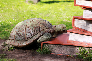 Sculpture of a turtle climbing on pile of books