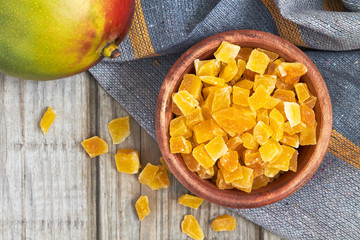 Dried and candied mango in wooden bowl. Top view with copy space