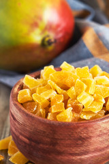 Closeup of dried and candied mango in wooden bowl