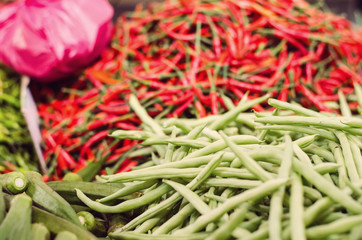 fresh raw green string bean over red chilies and lady fingers background.