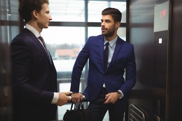 Businessmen interacting with each other in elevator
