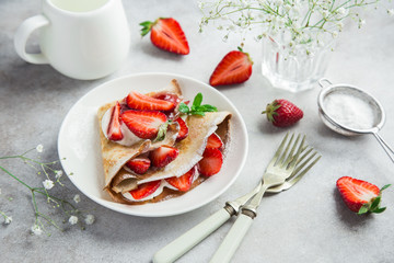 delicious crepe with cream cheese and fresh strawberry on white plate