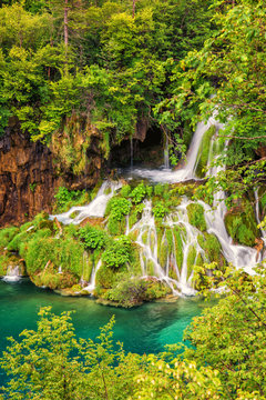 Beautiful waterfall in a green forest, Plitvice Lakes National Park, famous tourist destination in Croatia, nature background suitable for wallpaper, cover or guide book, vertical image