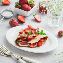 crepe served with cream cheese and fresh strawberry on white plate