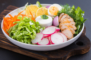  Mix of vegetables with saur cream sauce on a white plate. Clean eating. Raw vegetables and yogurt dressing in a white plate on wooden board.