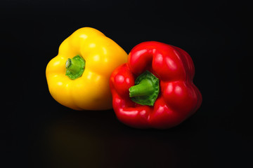 organic red and yellow bell peppers on black background