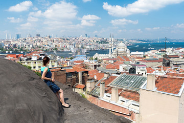 Fototapeta na wymiar girl standing on the roof and looking at city Istanbul