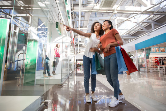 Two Excited Black Girls Pointing At Shop Window