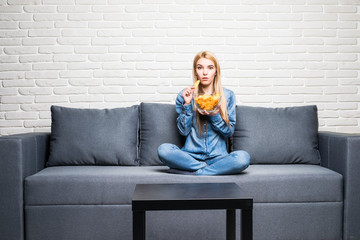 Young woman watching TV and eating chips at home