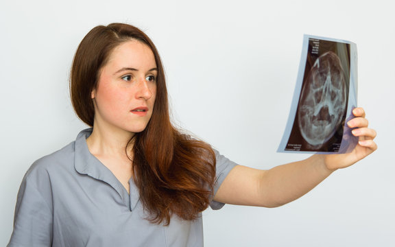 Young female doctor looking at the x-ray picture on white background