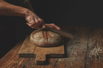 Men's hands cut bread