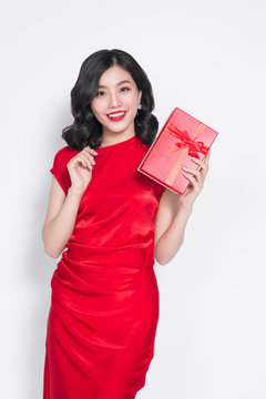 Pretty young glamorous asian woman dressed in red dress with a present
