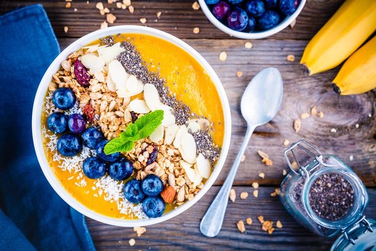Mango smoothies bowl with blueberries, granola, chia seeds and almonds
