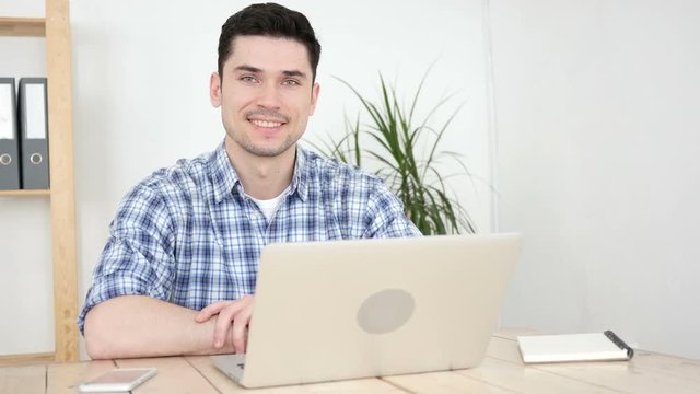 Man Working on Laptop Smiling  toward Camera