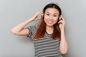 Cheerful young pretty woman listening music with headphones