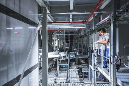 Two men talking in automatized high rack warehouse