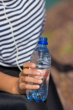 A bottle of water close-up. The girl drinks water during fitness outdoors