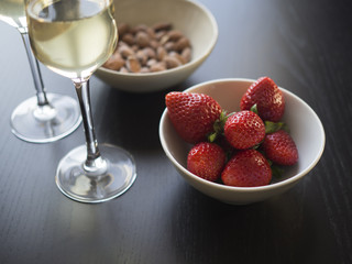 Two glasses of sparkling wine with red strawberries and roasted almonds. Isolated on black background