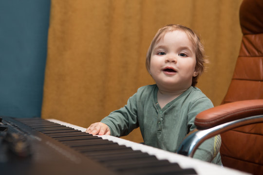 Baby  playing a piano synthesizer. Training of the child in music. Home studio.
