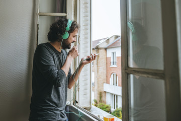 Man talking on cell phone in his room by the window