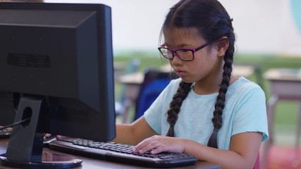 Young girl in school classroom working on computer - Powered by Adobe