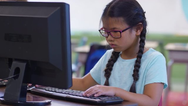 Young girl in school classroom working on computer