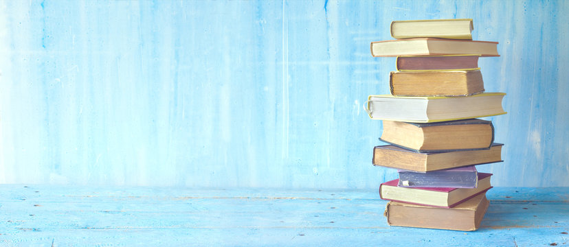 stack of books on blue grungy background, panoramic, good copy space