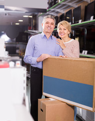 cheerful mature married couple in shop packed household appliances into boxes