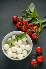 Mozzarella cheese, basil and tomatoes cherry on a gray background