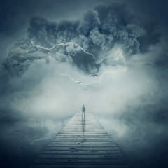 Fantastic view as a man, stand on the wooden pier at the middle of the lake in a foggy and stormy...