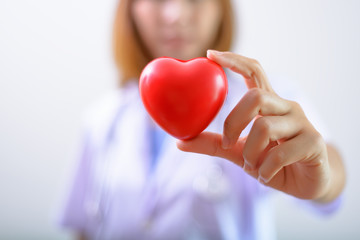 Female doctor holding a red heart shape with stethoscope. Health insurance and love concept.