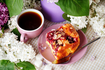 Still life with branches of lilac and a Cup of coffee on a wooden table.